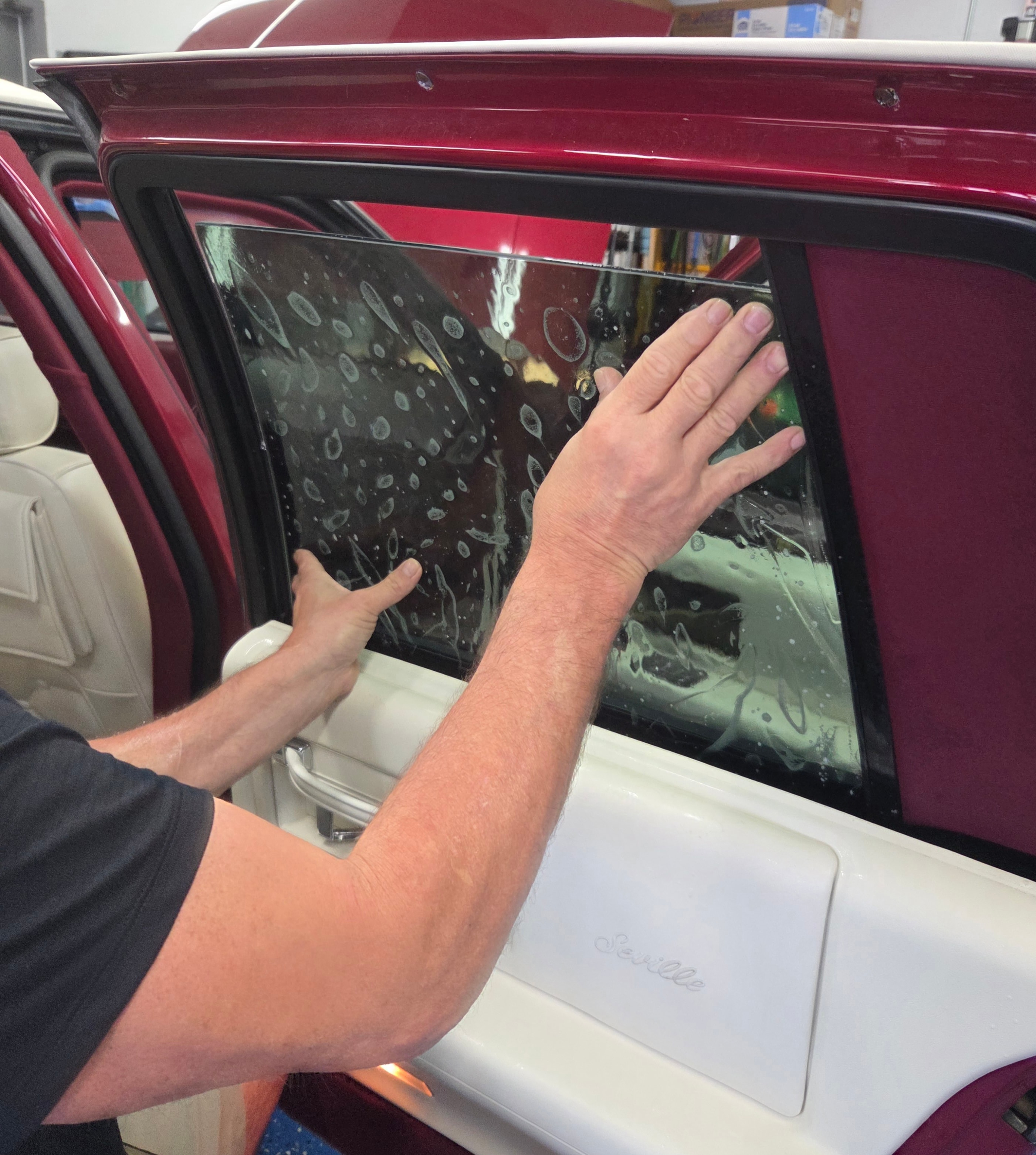 Professional installer applying LLumar window tint film to a car